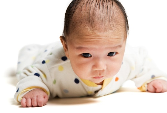 Bebê deitado de barriga para baixo com a cabeça levantada (tummy time) - Foto: arek_malang/Shutterstock.com