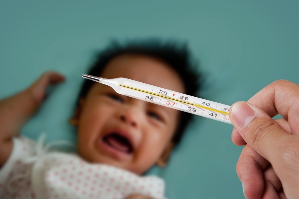 Bebê chorando ao fundo e termômetro sendo mostrado - Foto: phloxii/Shutterstock.com