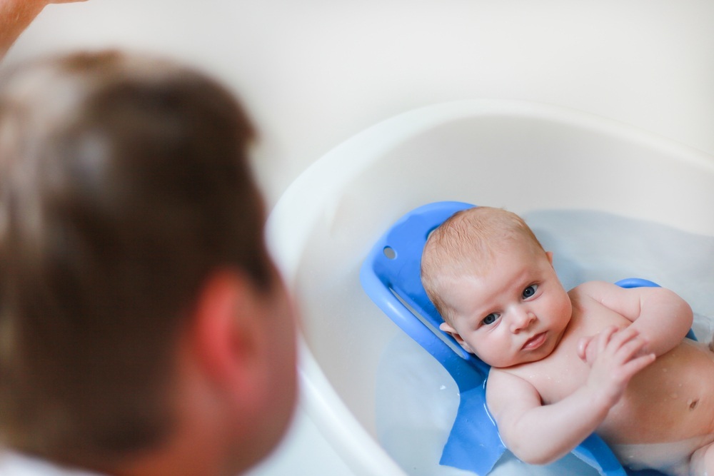 Bebê na banheira sendo observado pelo pai - Foto: Irina Schmidt/Shutterstock.com