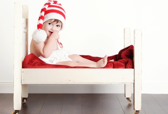 Criança sentada em uma cama pequenina - Foto: Melanie DeFazio/Shutterstock.com