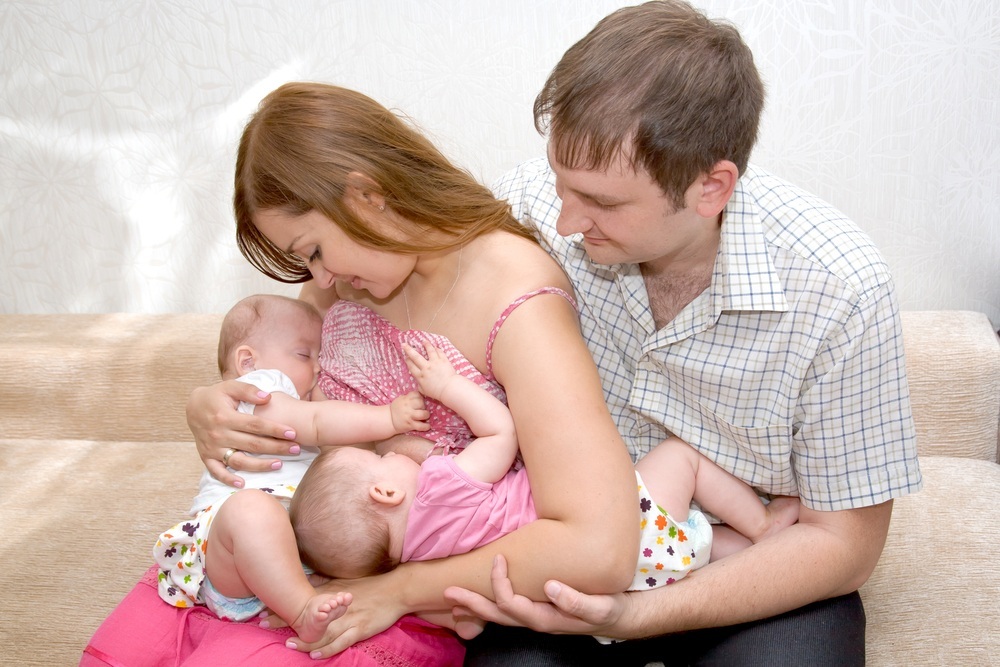 Mãe amamentando gêmeos com a ajuda do pai - foto: Vitalinka/ShutterStock.com