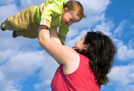 Mãe brincando de jogar o bebê para o alto - foto: SergiyN/ShutterStock.com