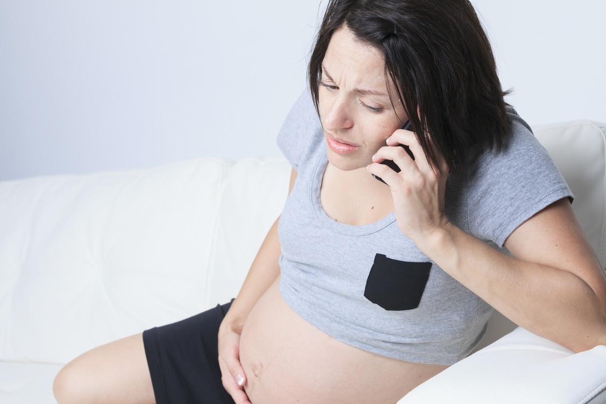Mulher grávida sentada usando o telefone - foto: Lopolo/ShutterStock.com
