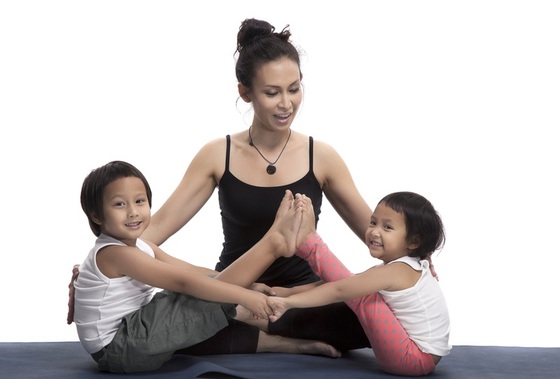 Crianças fazendo yoga com ajuda da professora - Foto: Surrphoto/ShutterStock.com