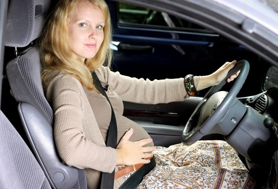 Gestante no carro ao volante utilizando o cinto de segurança - Foto: ambrozinio/Shutterstock.com