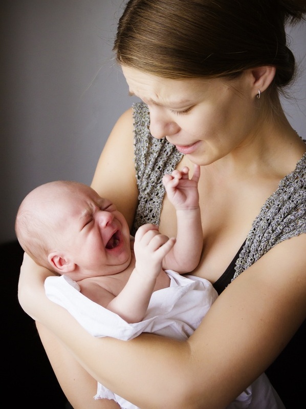 Bebê chorando no colo da mãe que está apreensiva - Foto: Nadezhda Sundikova/Shutterstock.com