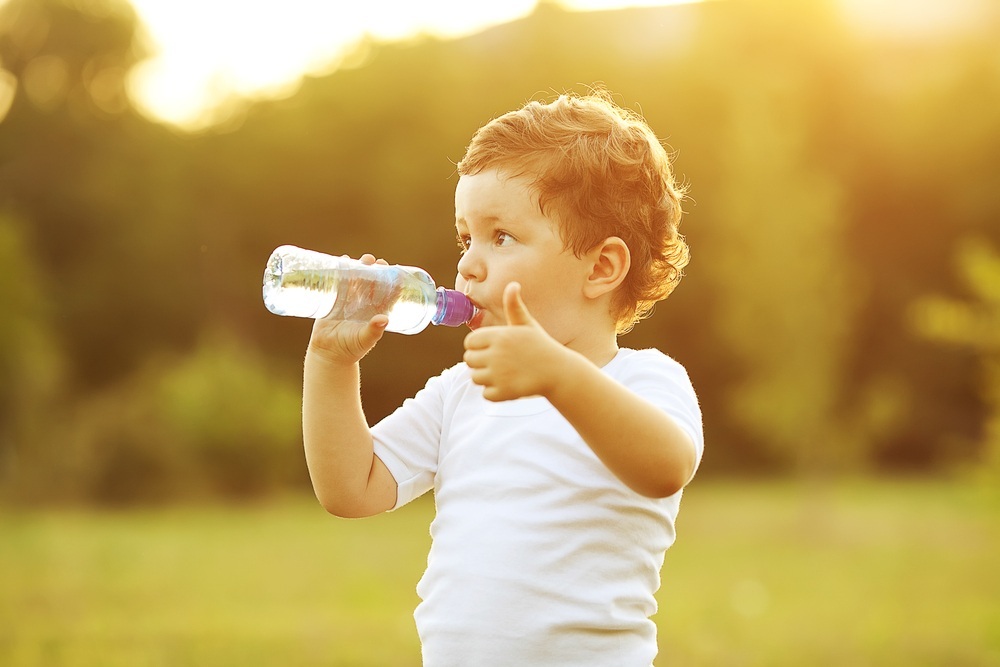 Criança bebendo água na garrafa e fazendo sinal de positivo - foto: Selins/ShutterStock.com
