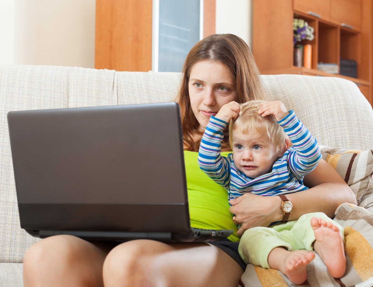Mãe com bebê no colo utilizando o computador - foto: Iakov Filimonov/ShutterStock.com