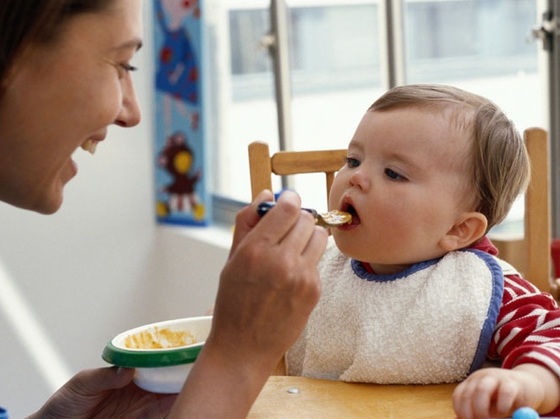 Mamãe dando papinha na boca do bebê - Getty Images