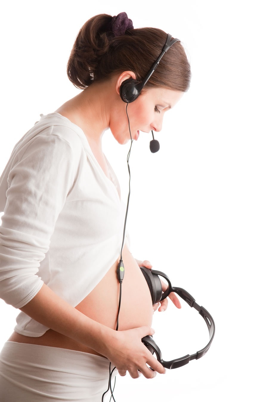 Mulher grávida falando com o bebê utilizando fones e microfones - foto: MariyaL/ShutterStock.com