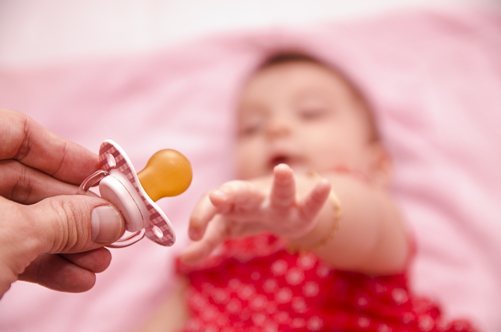 Bebê tentando pegar a chupeta - foto: maxriesgo/ShutterStock.com