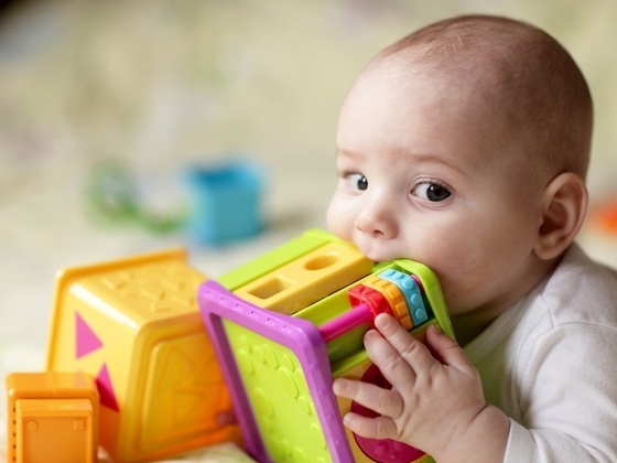Bebê colocando o brinquedo na boca - Chubykin Arkady / Shutterstock