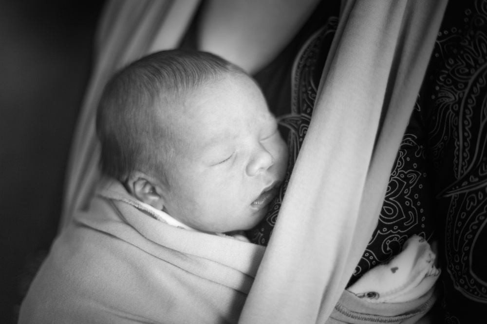Bebê no colo da mãe em um sling (canguru) - foto: Natalia Lebedinskaia/ShutterStock.com