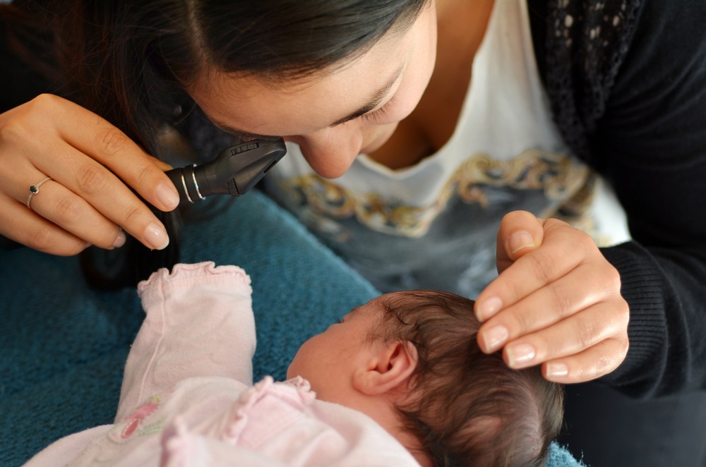 Médica realizando exame do reflexo vermelho no olho do bebê - foto: ChameleonsEye/ShutterStock.com