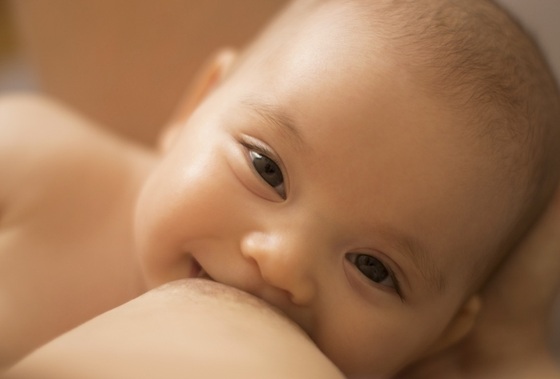 Bebê mamando e sorrindo - foto: Topuria Design/ShutterStock.com