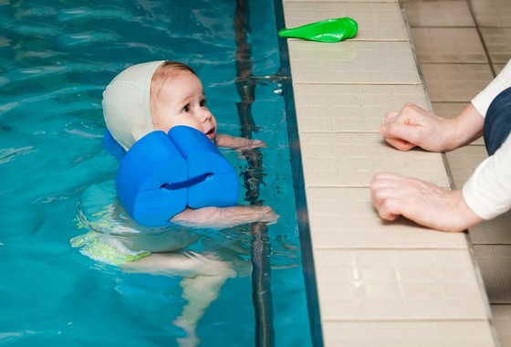 Bebê dentro da piscina observando o adulto fora da psicina - Foto: dien/ShutterStock.com