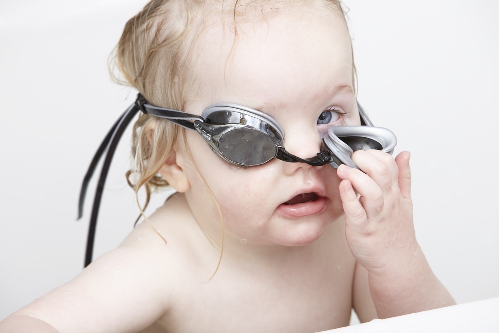 Bebê mexendo no óculos de natação - Foto: sanneberg/ShutterStock.com