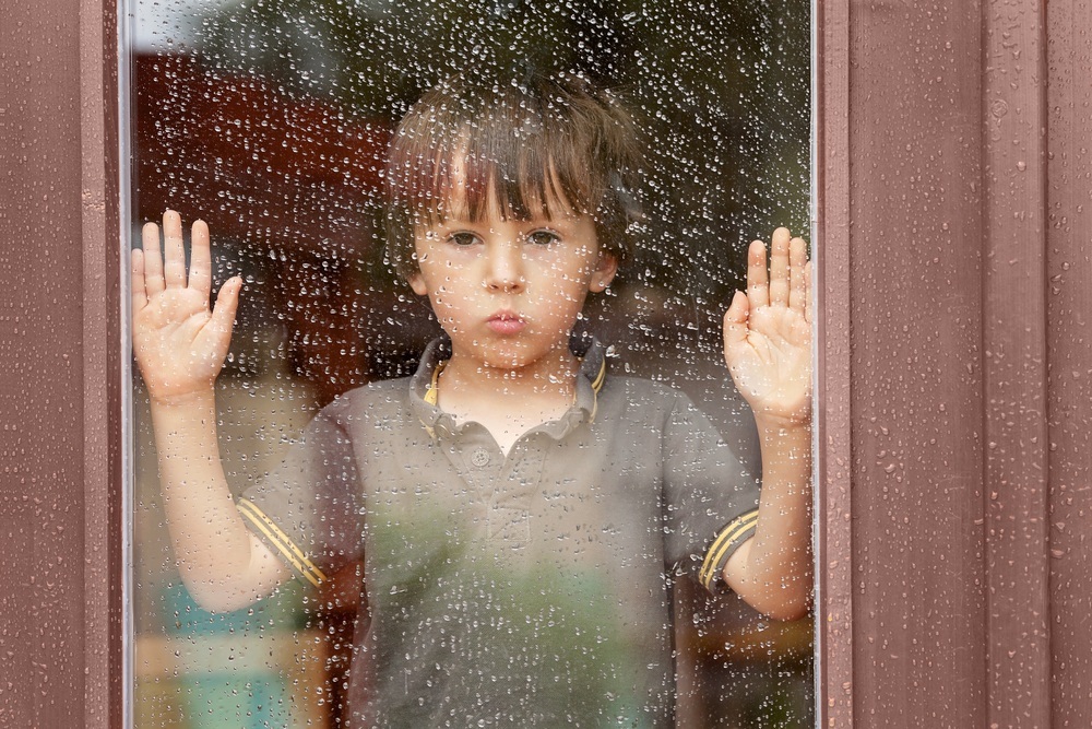 Garoto atrás da janela em dua chuvoso - foto: Tomsickova Tatyana/ShutterStock.com