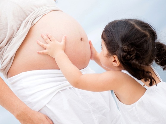Criança segurando com carinho a barriga da mamãe grávida - Foto: Andresr/ShutterStock