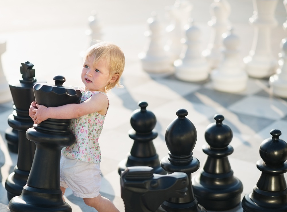 Criança movendo peça gigante de xadrez - Foto: Alliance/Shutterstock.com