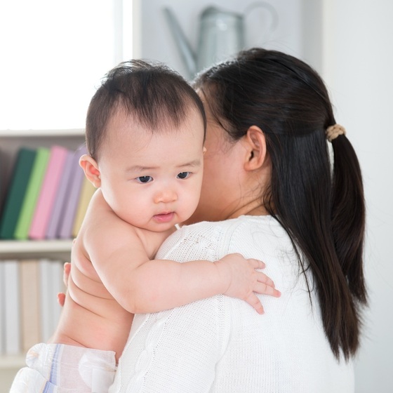 Mãe segurando o bebê no colo na posição vertical - foto: szefei/ShutterStock.com