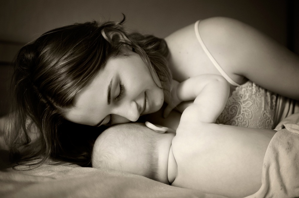 Mamãe deitada ao lado de seu bebê enquanto ele mama - Foto: Natalia Deksbakh / ShutterStock.com