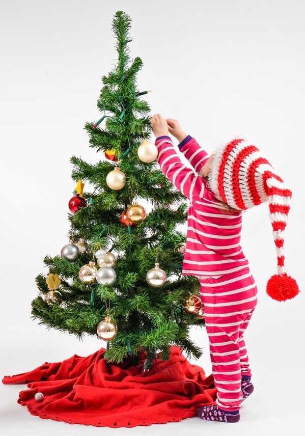 Criança decorando a Árvore de Natal - Foto: JGA/ShutterStock.com