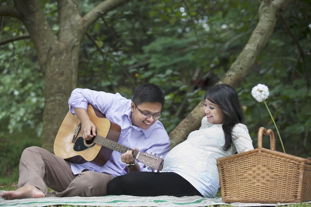 Pai tocando violão para sua esposa grávida - foto: Creativa Images/ShutterStock.com