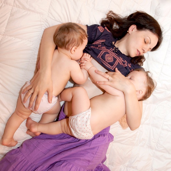 Mãe deitada amamentando gêmeos - foto: Vitalinka/ShutterStock.com